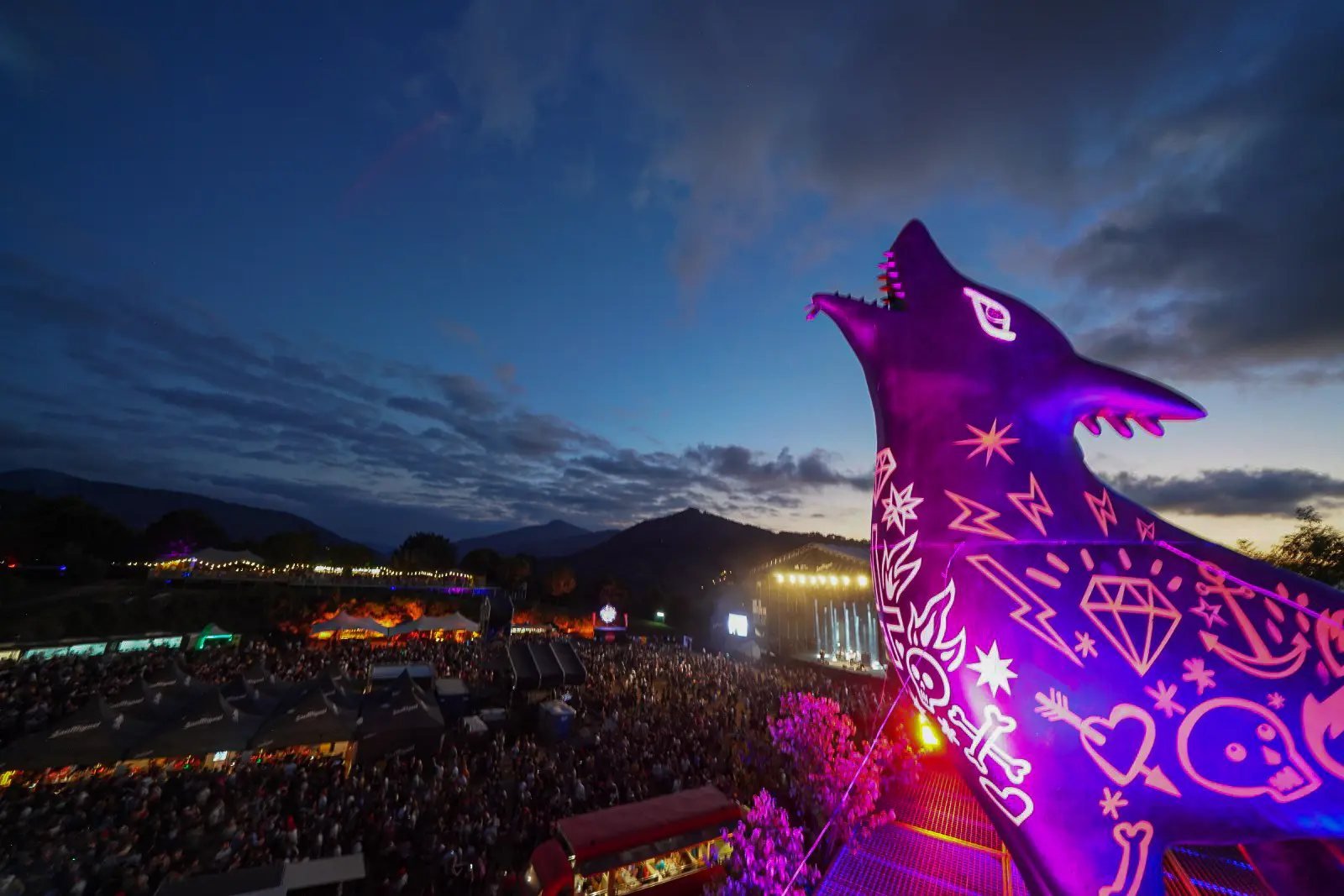 Festival site at dusk with a large illuminated wolf sculpture at Bilbao BBK Live